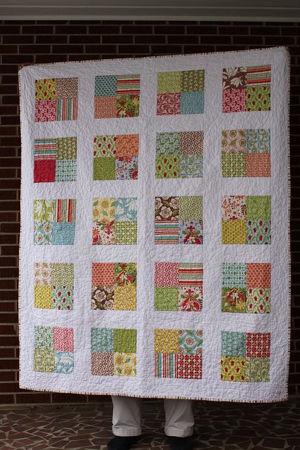 a person holding up a large quilt