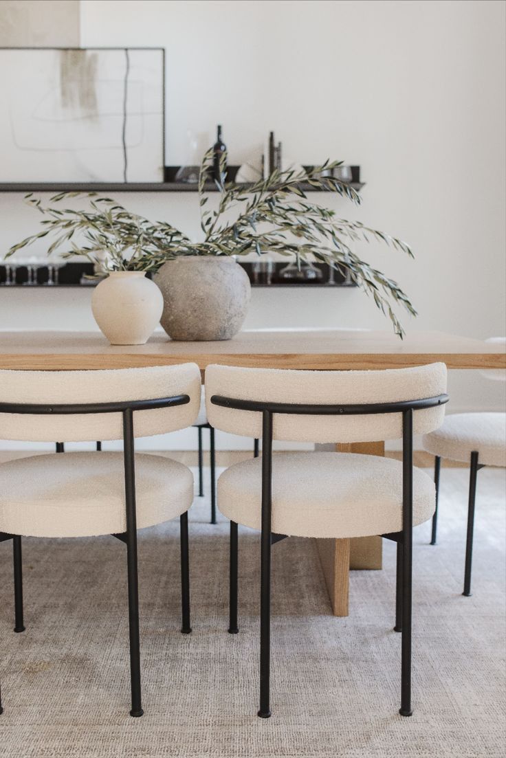 a dining room table with four chairs and a vase on the top of it in front of a mirror