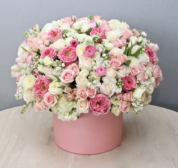 a pink and white flower arrangement sitting on a table