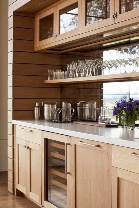 a kitchen filled with lots of wooden cabinets and wine glasses on top of the counter