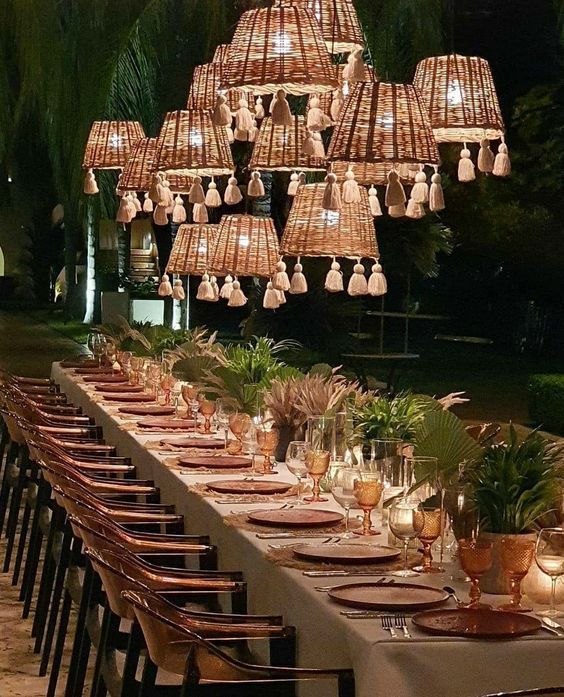 a long table with many plates and place settings on it, surrounded by hanging lights