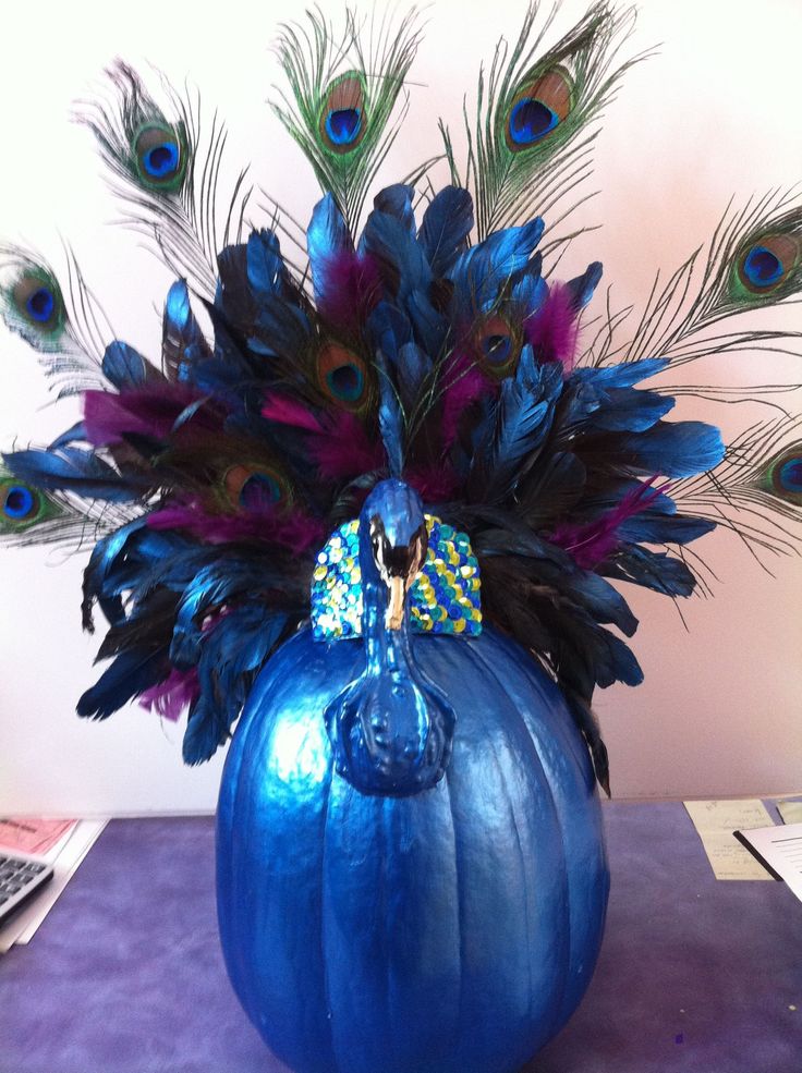 a blue pumpkin with peacock feathers in it