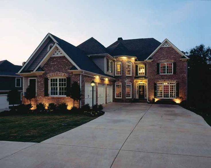 a large brick house with lights on the front door and windows in the side yard