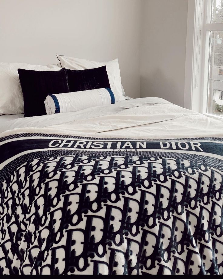 a bed with white sheets and black pillows in a bedroom next to a large window