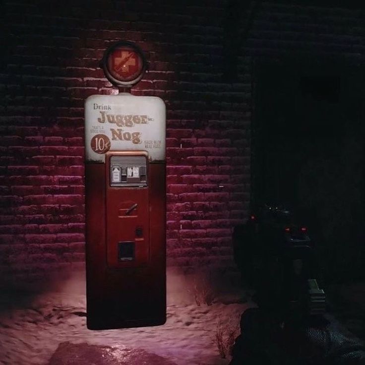 a red and white machine sitting next to a brick wall with a clock on it