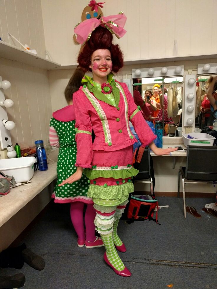 a woman in pink and green dress standing next to a counter