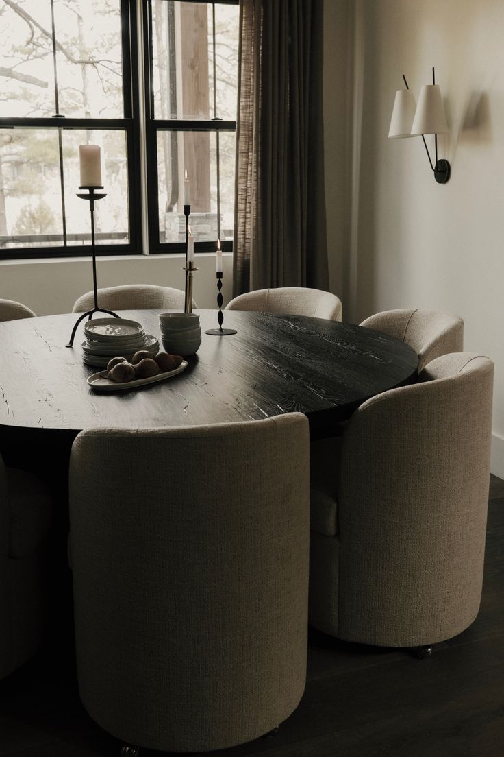 a dining room table with chairs and a candle on the table in front of a window