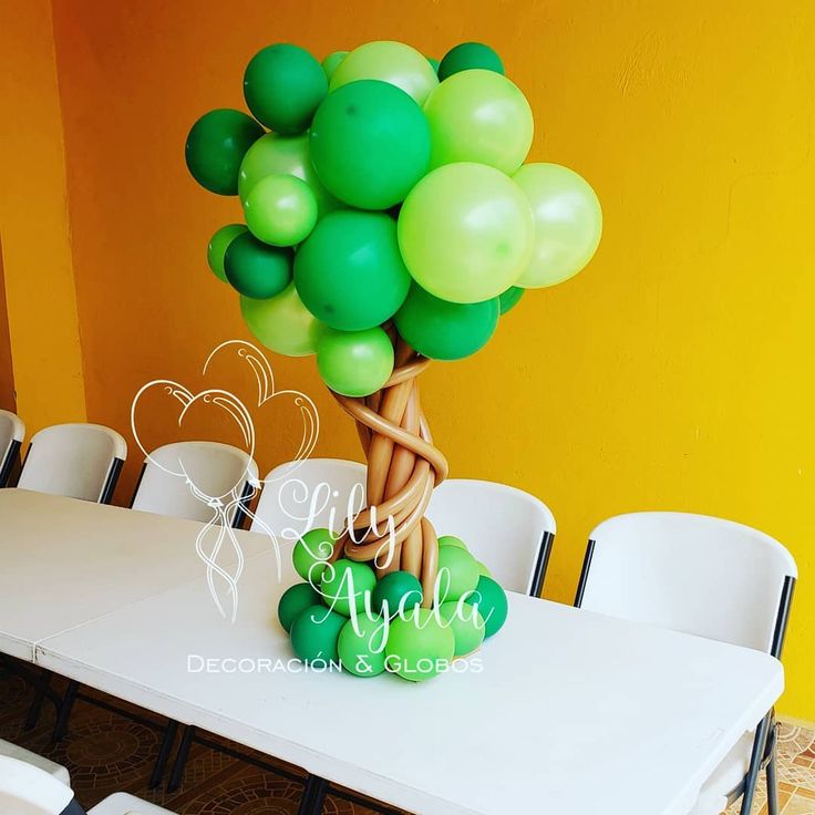 there is a table with some balloons on it and a tree in front of the table