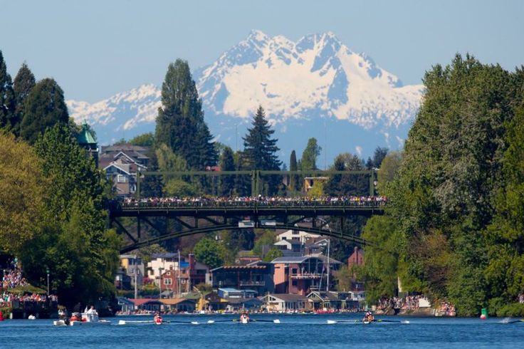 a bridge over the water with boats on it and snow capped mountains in the background