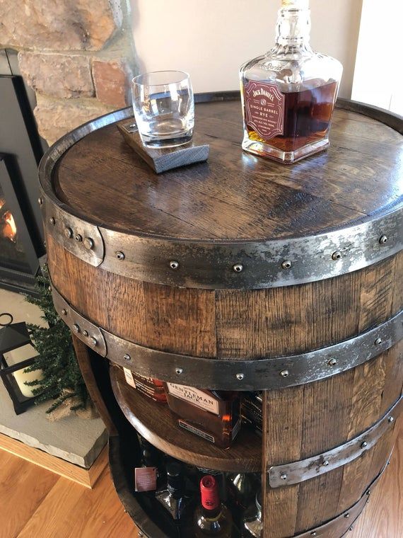 a wooden barrel table with two bottles on it and a glass bottle in the middle