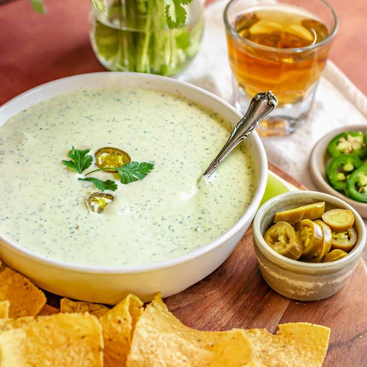 a bowl of dip surrounded by tortilla chips, salsa and celery