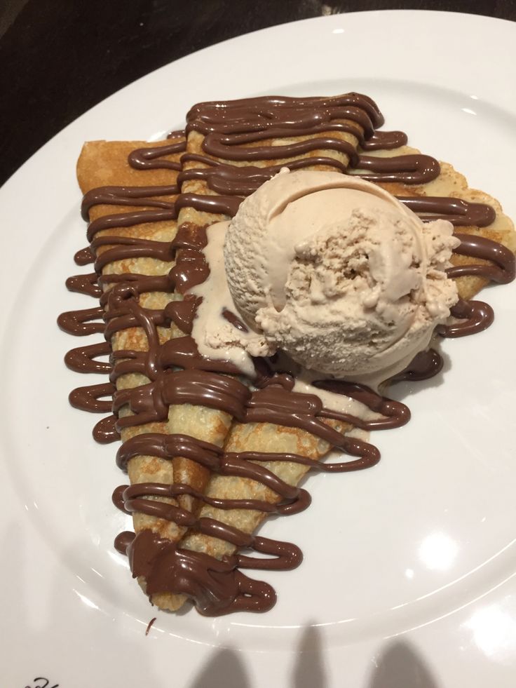 a white plate topped with waffles covered in chocolate sauce and icecream