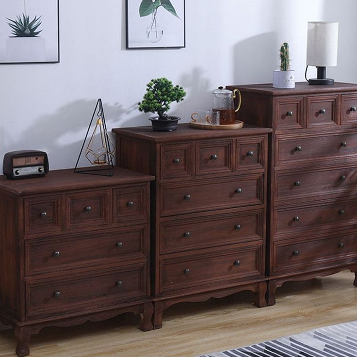 a wooden dresser sitting on top of a hard wood floor next to a white wall