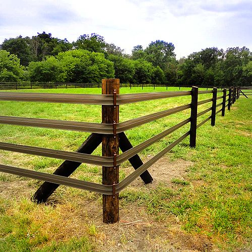 a wooden fence in the middle of a grassy field