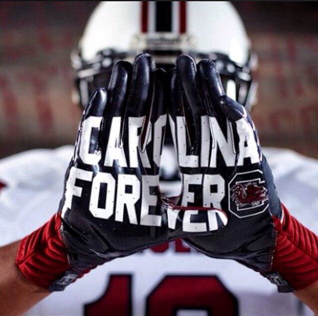 a close up of a football player's hands with the words carolina forever on it