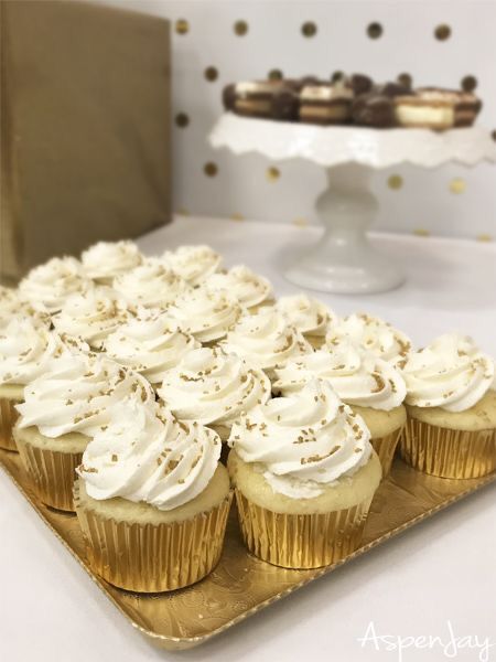 cupcakes with white frosting and sprinkles on a gold tray