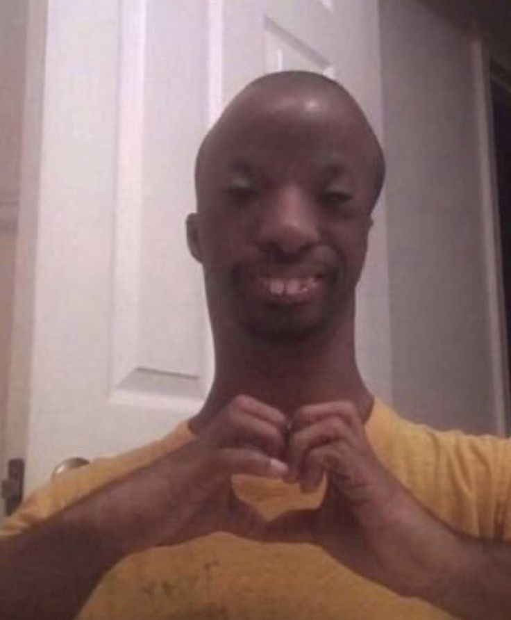 a man is smiling and holding his hands together in the shape of a heart while standing in front of a door