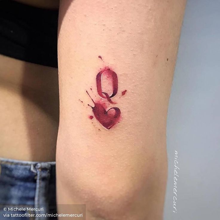 a woman's thigh with a heart tattoo on her left leg and the letter q painted in red ink