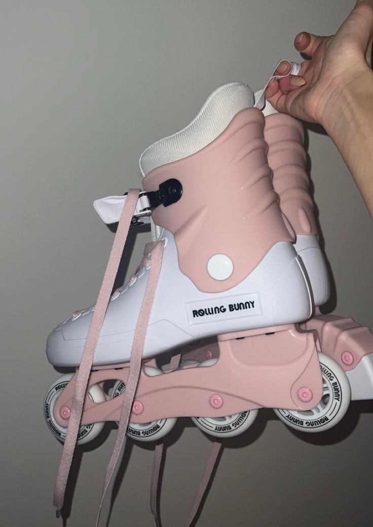 someone is holding on to roller skates that are pink and white