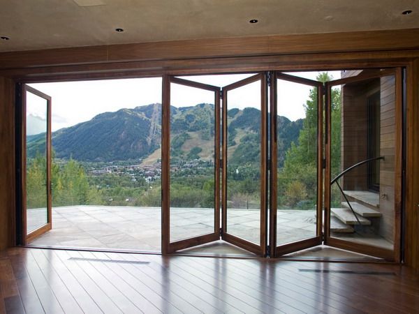 an open room with wooden floors and sliding glass doors that lead to a mountain view