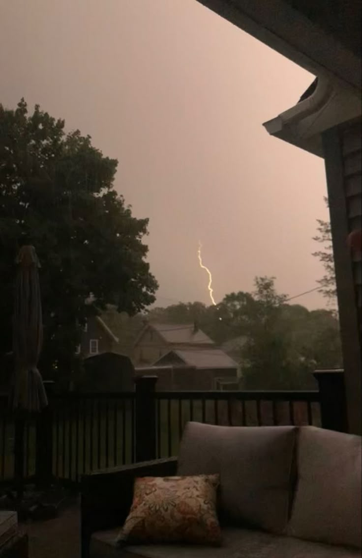 a lightning bolt is seen in the distance from a porch