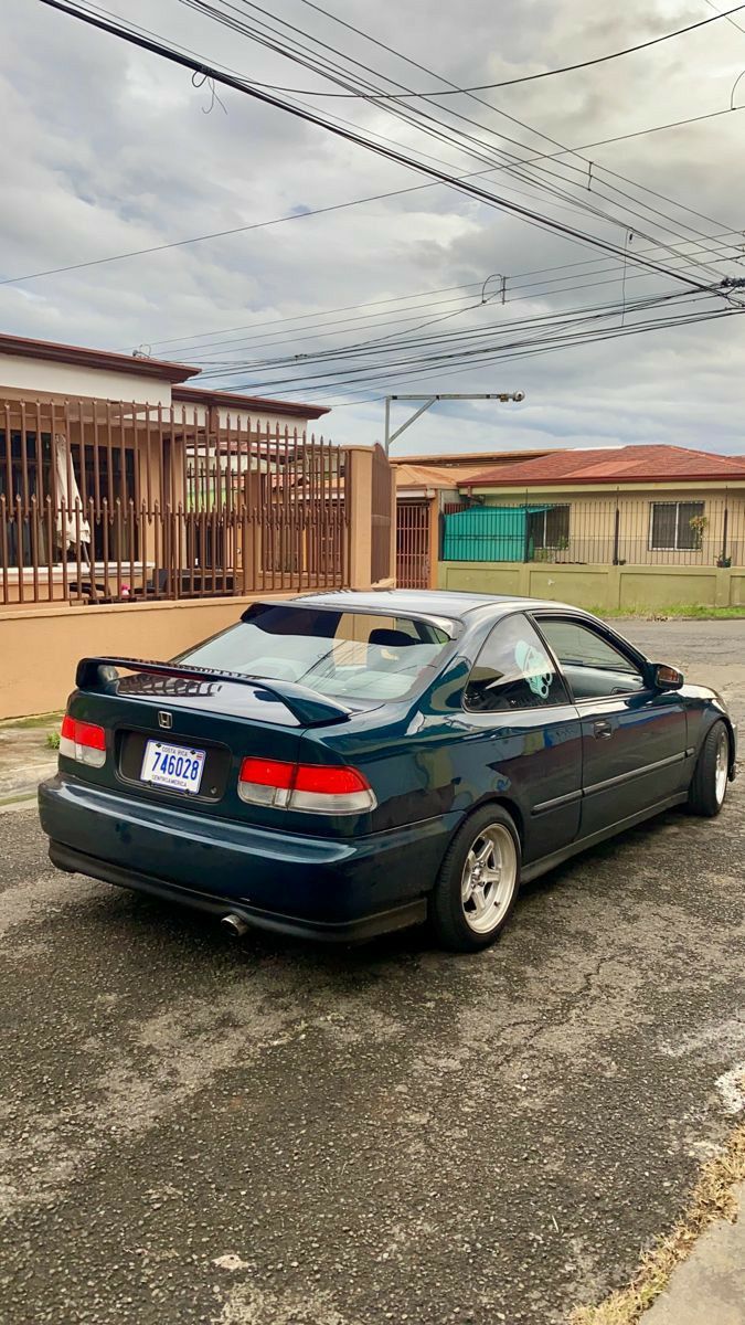 a black car parked in front of a building on the side of the road with power lines above it