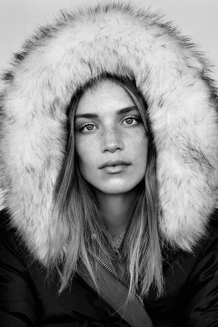 black and white photograph of a woman wearing a hooded jacket with fur hood over her head