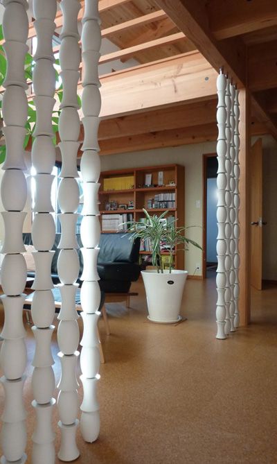 a living room filled with lots of furniture and tall white columns in the middle of it