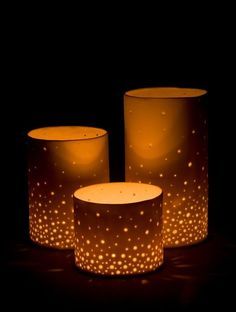 three lit candles sitting next to each other on a black surface with white dots all over them