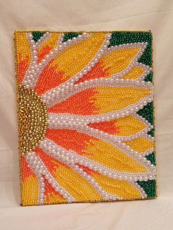 a beaded square with an orange and yellow flower on it