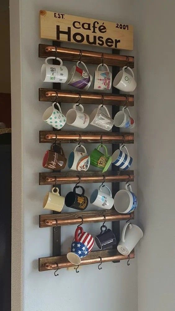 a wooden rack with cups and mugs hanging from it's sides on the wall