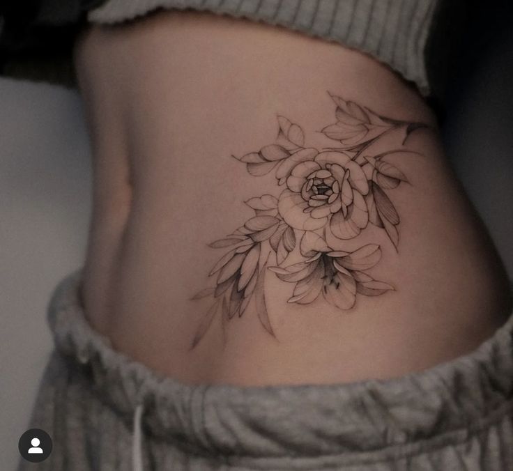 a woman's stomach with a flower tattoo on her belly and the bottom part of her abdomen