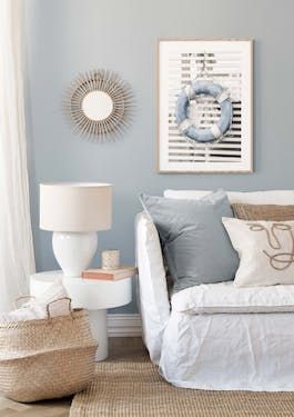 a white couch sitting in a living room next to a lamp and pictures on the wall