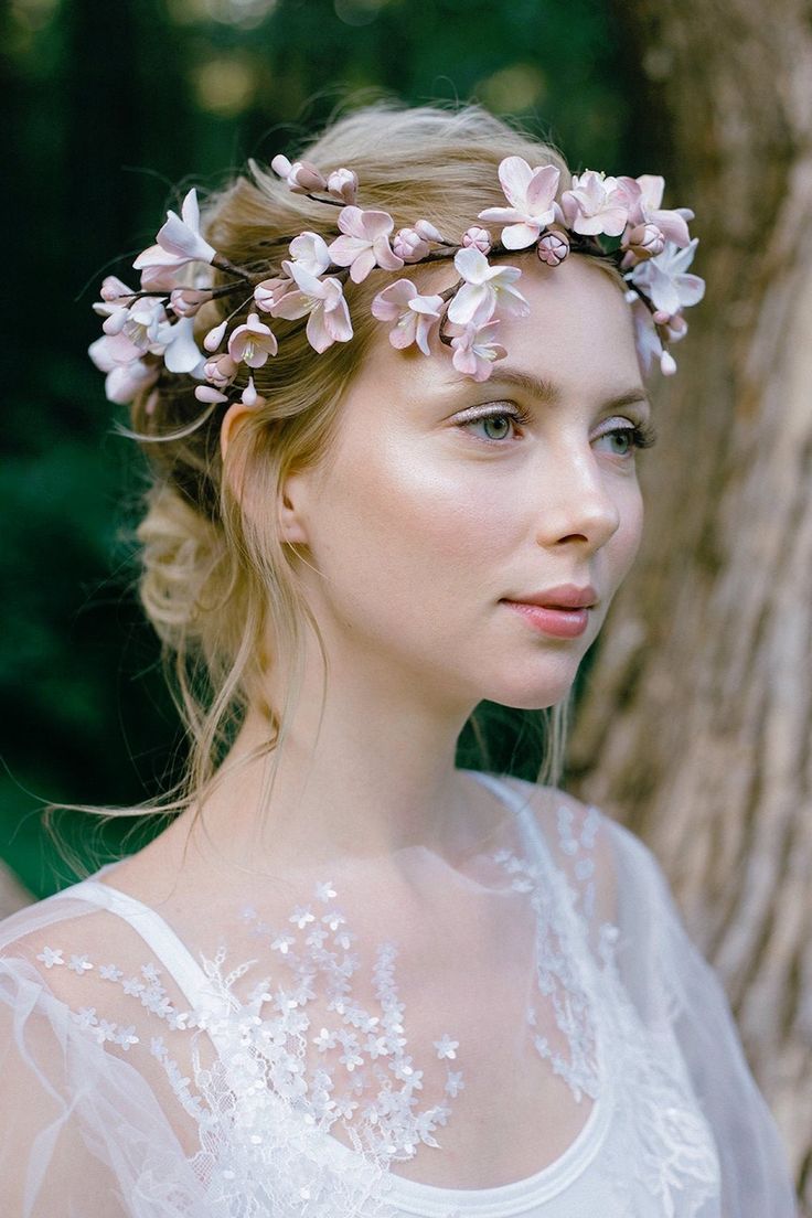 a woman wearing a flower crown in front of a tree