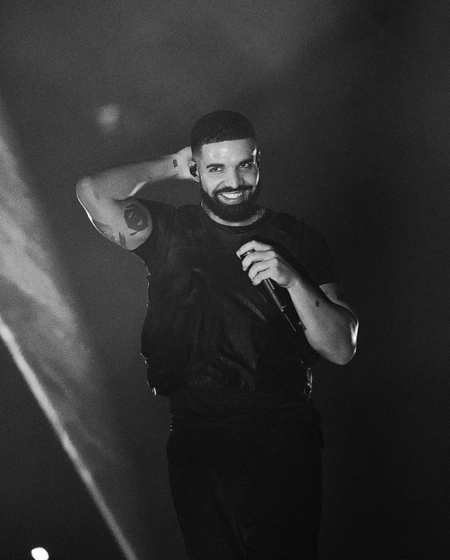 a man holding a microphone in his right hand and standing on stage with lights behind him