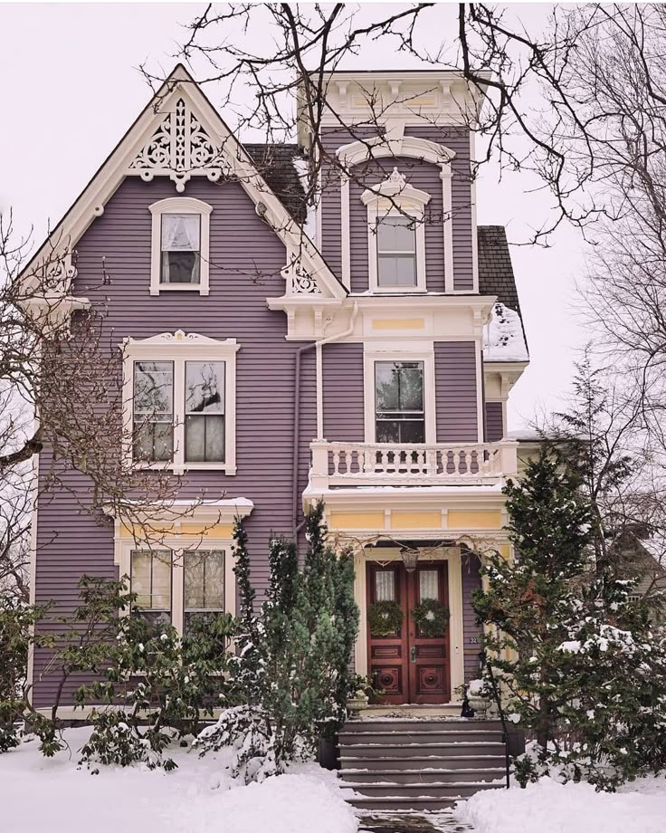 a purple house with snow on the ground and steps leading up to it's front door