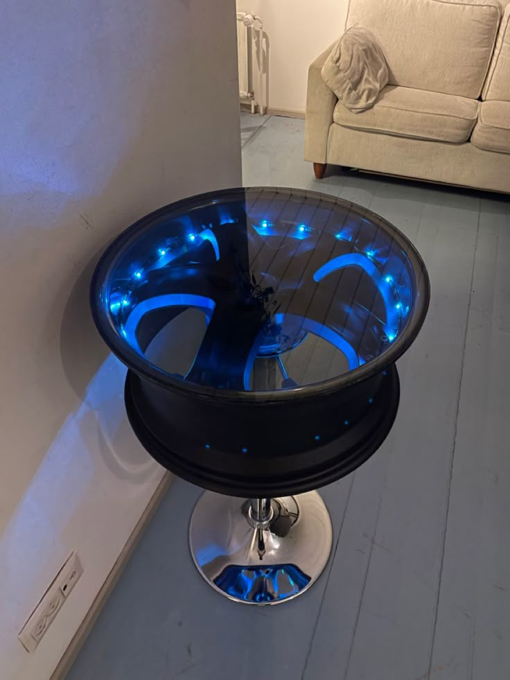 a glass table with blue lights on it in front of a white couch and wall