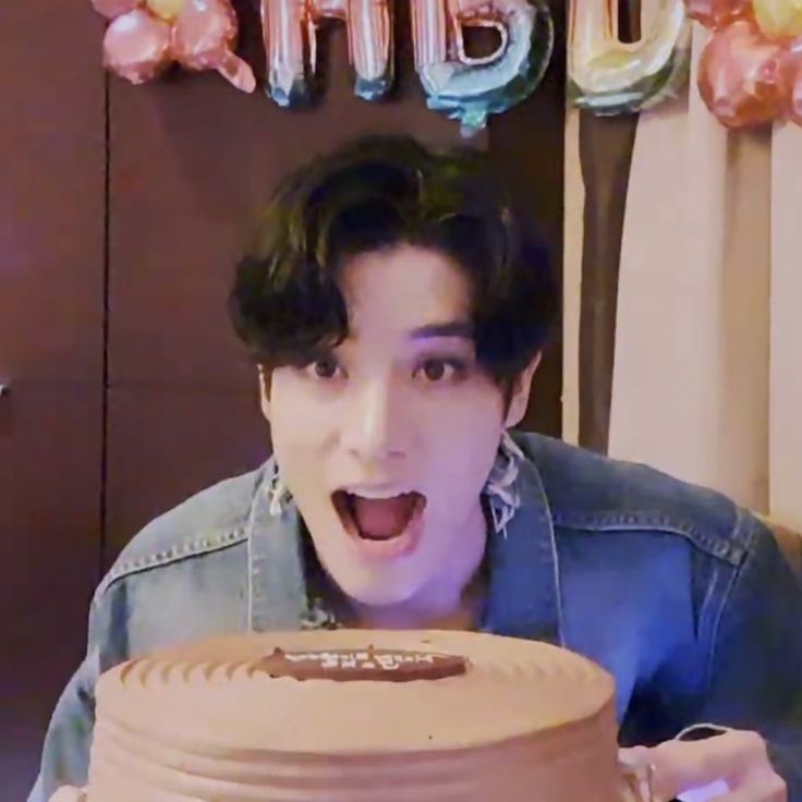 a young man holding a giant cake in front of him with his mouth wide open