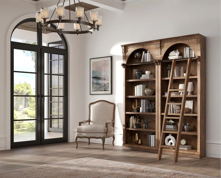 a living room with an open bookcase, chair and chandelier hanging from the ceiling