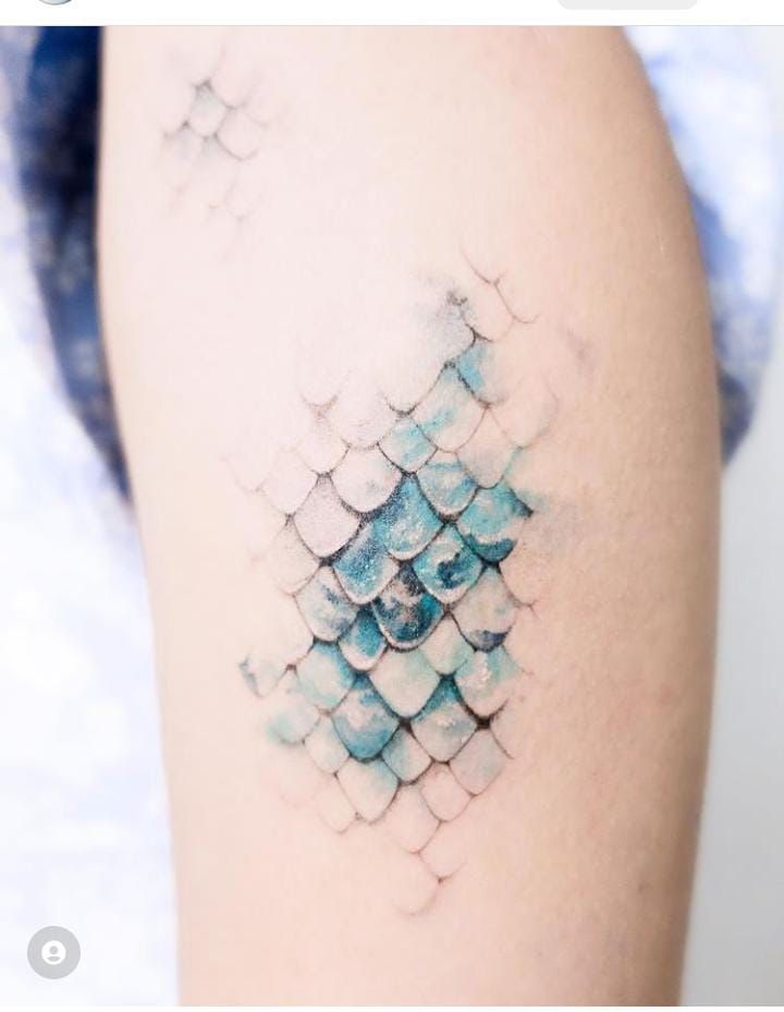 a woman's arm with a blue and white tattoo design on the back of it