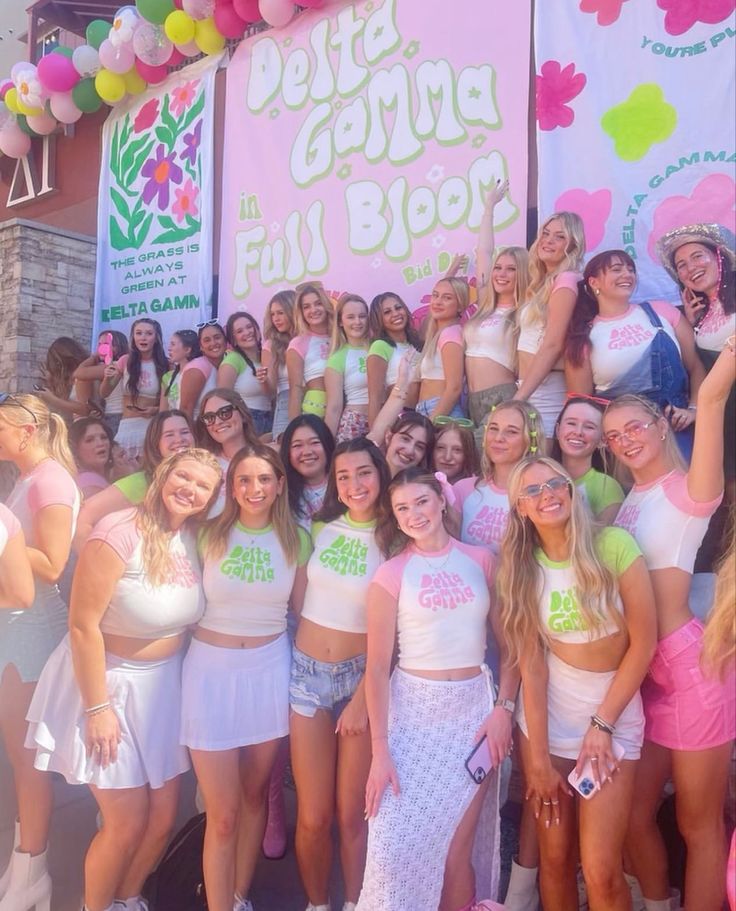 a group of young women standing next to each other in front of a pink and white sign