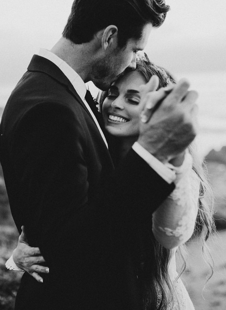 black and white photo of a bride and groom holding their arms around each other as they pose for the camera