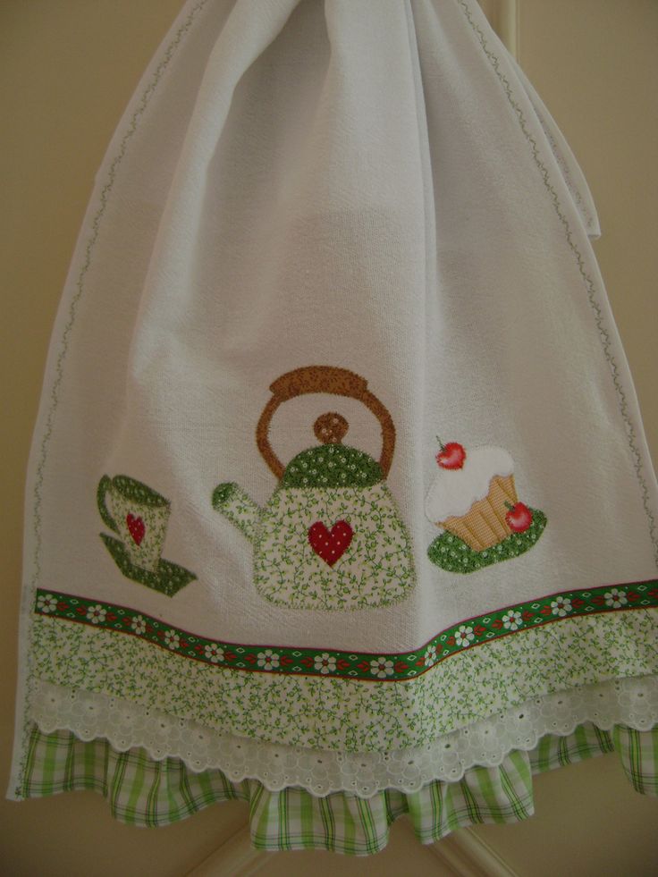 a kitchen towel hanging on the wall with a teapot and cupcakes embroidered on it