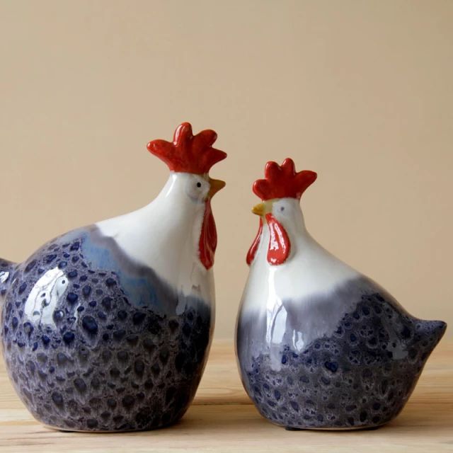 two blue and white rooster figurines sitting next to each other