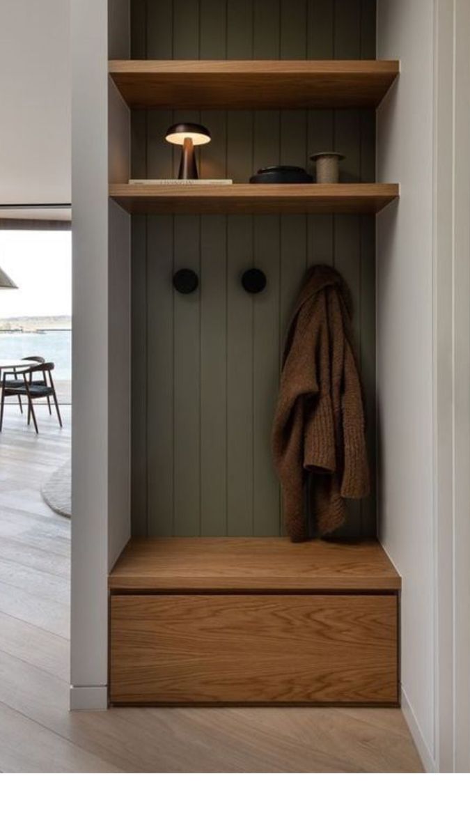 a coat rack with two coats hanging on it's sides and a table in the background