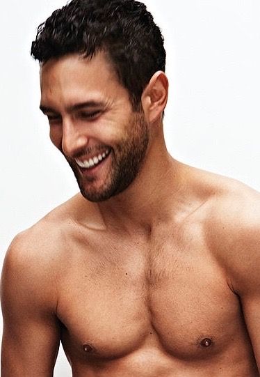 a shirtless man is smiling while holding a cell phone