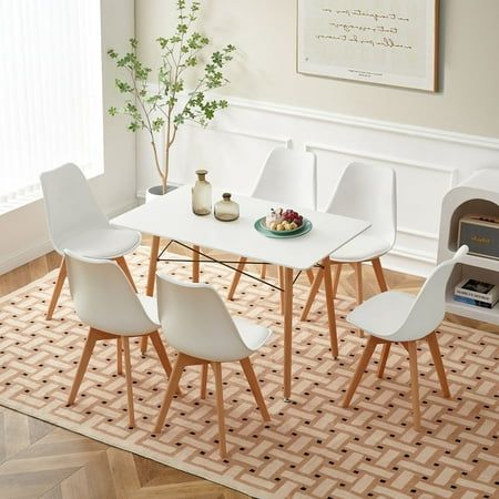 a dining room table with white chairs and a potted plant on top of it