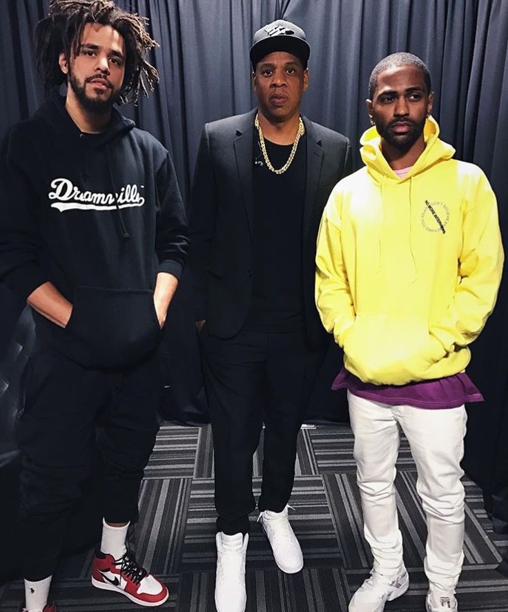 three young men standing next to each other in front of a black curtain with the word dream written on it