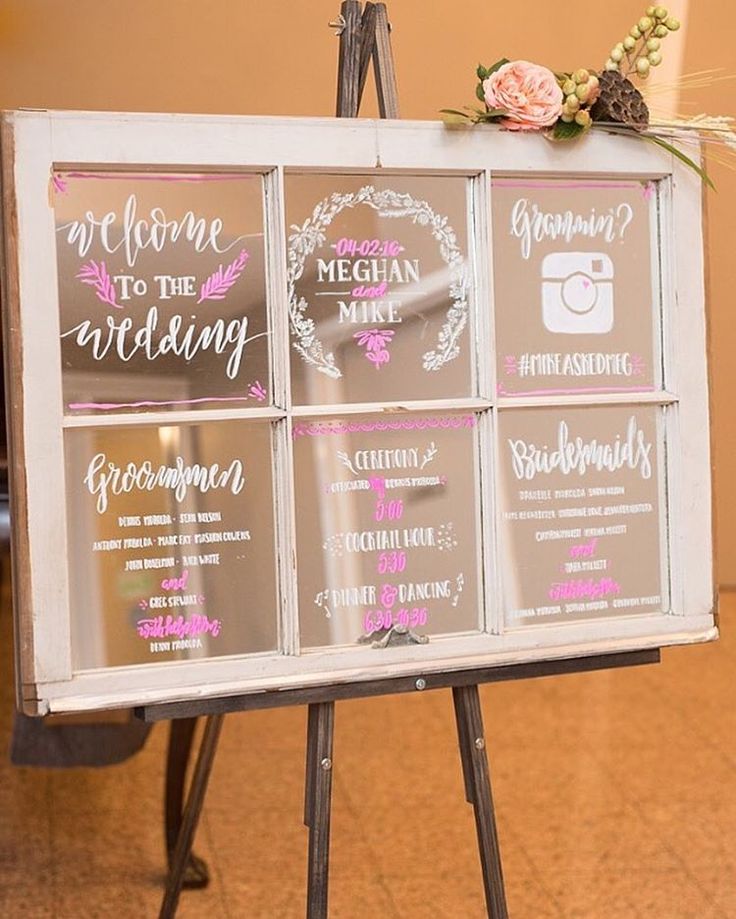 a sign that has been placed on top of a tripod with flowers in it