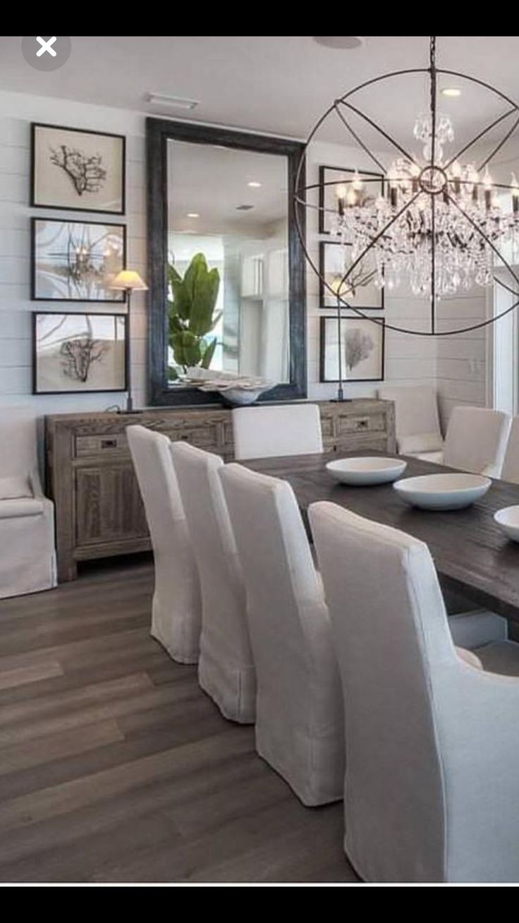 a dining room table with white chairs and a chandelier